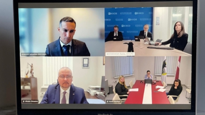 Datora ekrāns, kurā redzami četri logi: OECD pārstāvis, trīs EK pārstāvji, KNAB priekšnieks Jēkabs Straume un trīs KNAB pārstāves