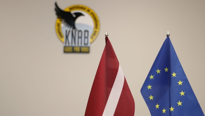Attēlā redzams Latvijas karogs, Eiropas Savienības karogs un KNAB logo