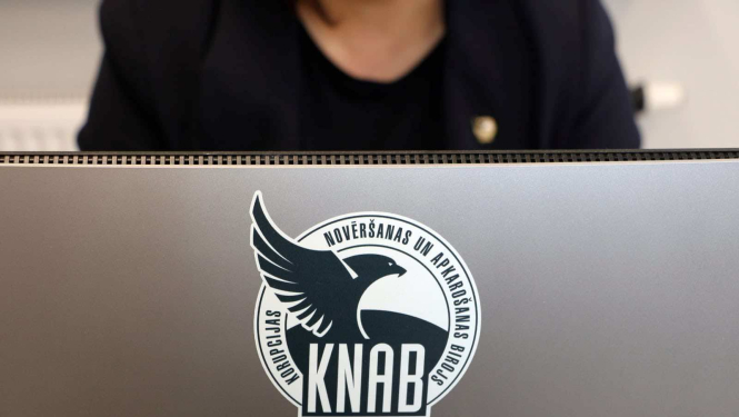 Attēlā redzams dators ar KNAB logo