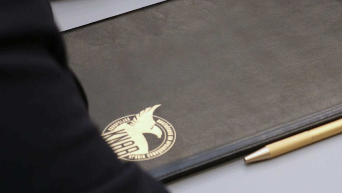 Attēlā redzama mape ar KNAB logo