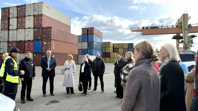 Attēlā redzami vairāk nekā desmit cilvēki, kas atrodas Rīgas brīvostas muitas kontroles punktā