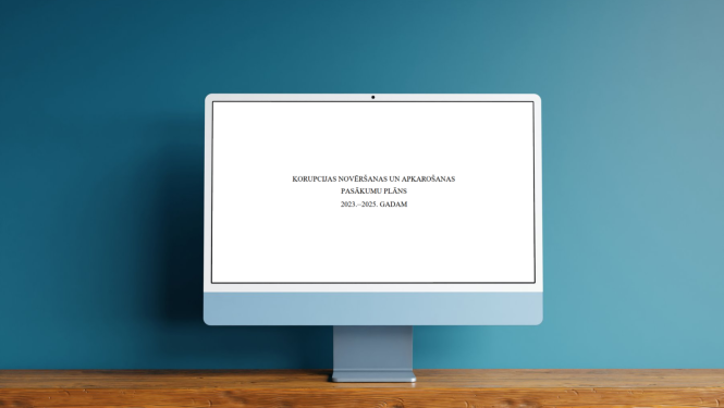 Uz galda datora monitors, kurā izlasāms "Korupcijas novēršanas un apkarošanas pasākumu plāns 2023.-2025. gadam"