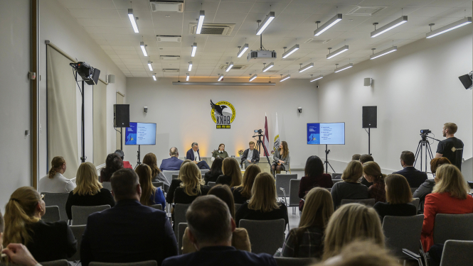 Conference room with the logo of KNAB. Participants sitting facing the logo