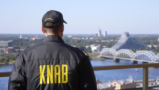 Vīrietis ar KNAB jaku uz jumta