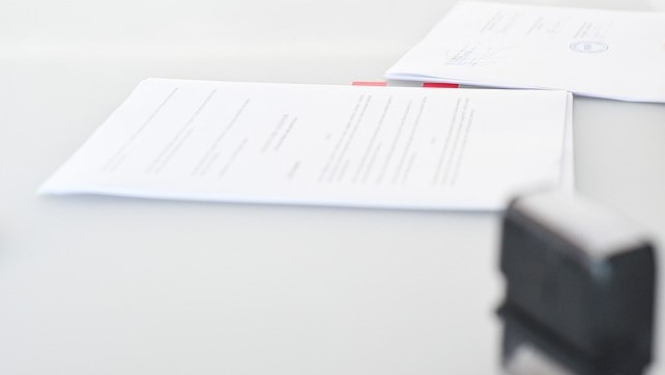 Attēlā redzamas papīra lapas un zīmogs