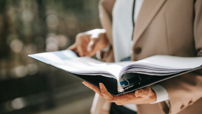 Attēlā redzama persona ar atvērtu dokumentu mapi